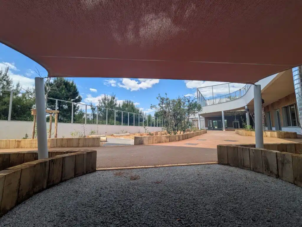 Voile d’ombrage Soltis 92 cuivre installée dans la cour du groupe scolaire Nouveau Saint Roch à Montpellier.