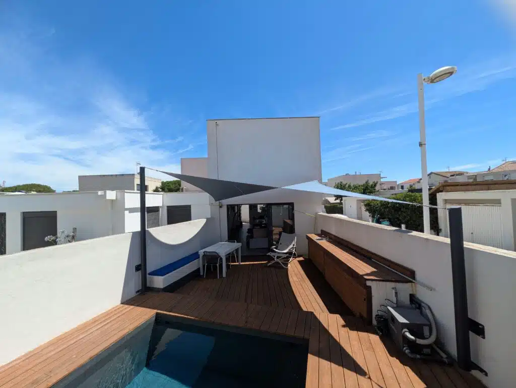 Voile d’ombrage Soltis 92 gris céleste installée sur une terrasse avec piscine à Carnon, près de Montpellier.