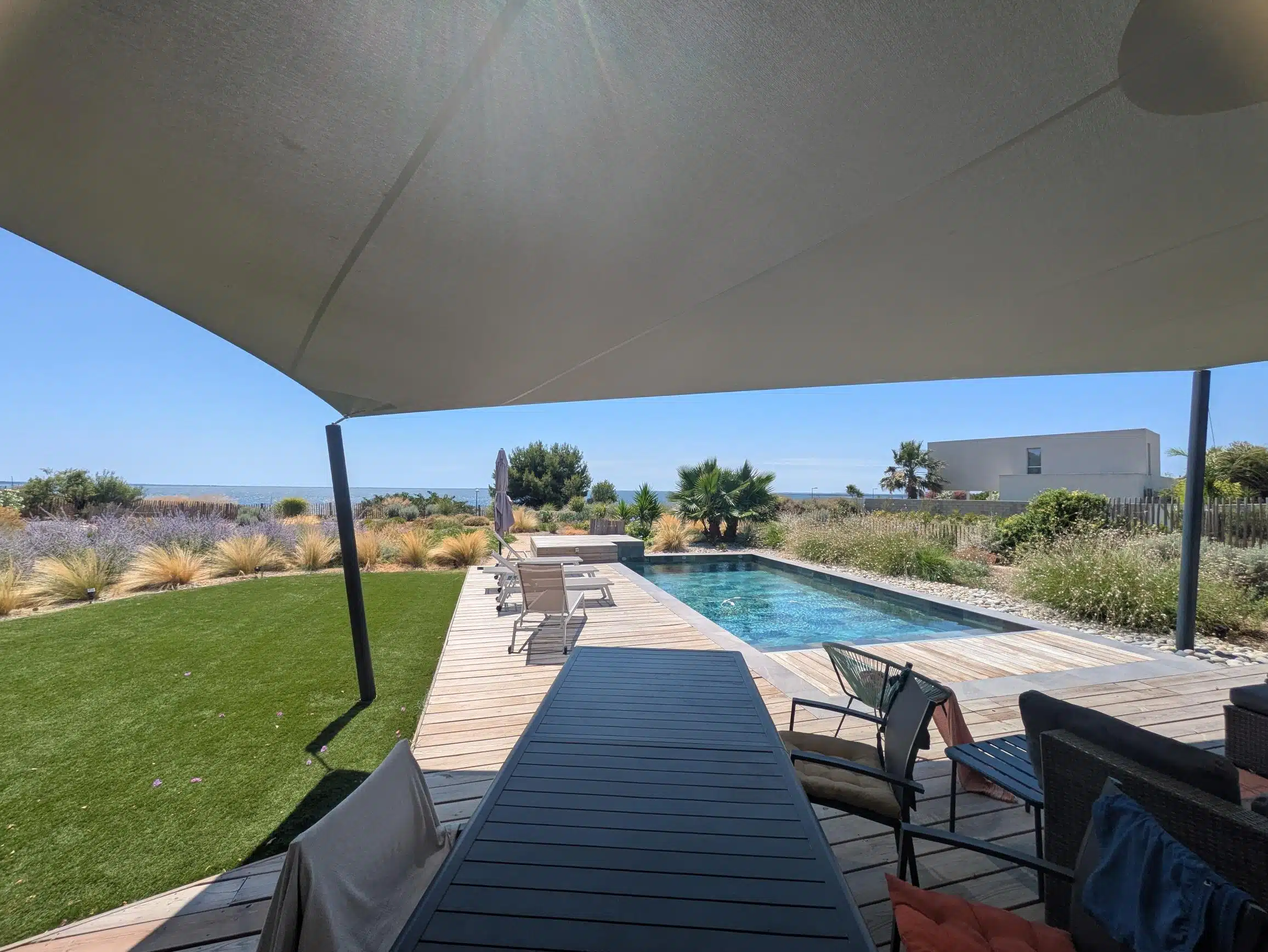 Voile 6 pointes Soltis 92 vert de gris installée sur une terrasse avec piscine à Mèze, au bord de l’étang de Thau.