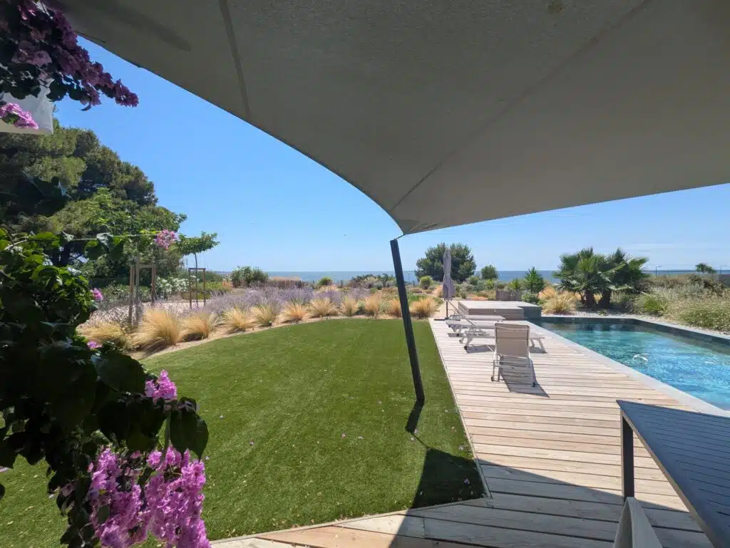 Terrasse avec pelouse et piscine ombragée par une voile Soltis 92 vert de gris à Mèze.